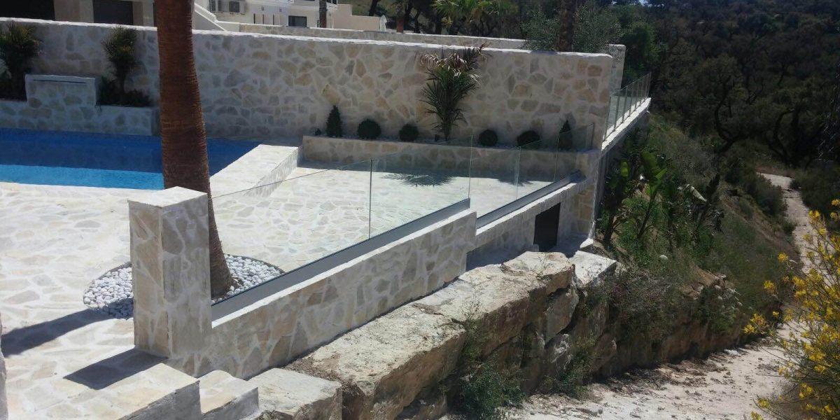 Casa hecha con mármol donde se puede apreciar las barandillas de cristal en el balcón