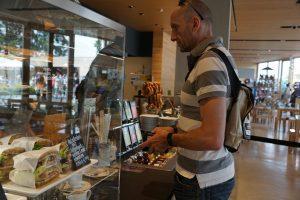 Escaparate de cristal de una cafetería situada en Terrassa donde el cliente está buscando el dinero para pagar