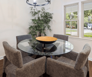 Mesa de Cristal con pufs de sofás para sentarse donde se puede apreciar la ventana abierta